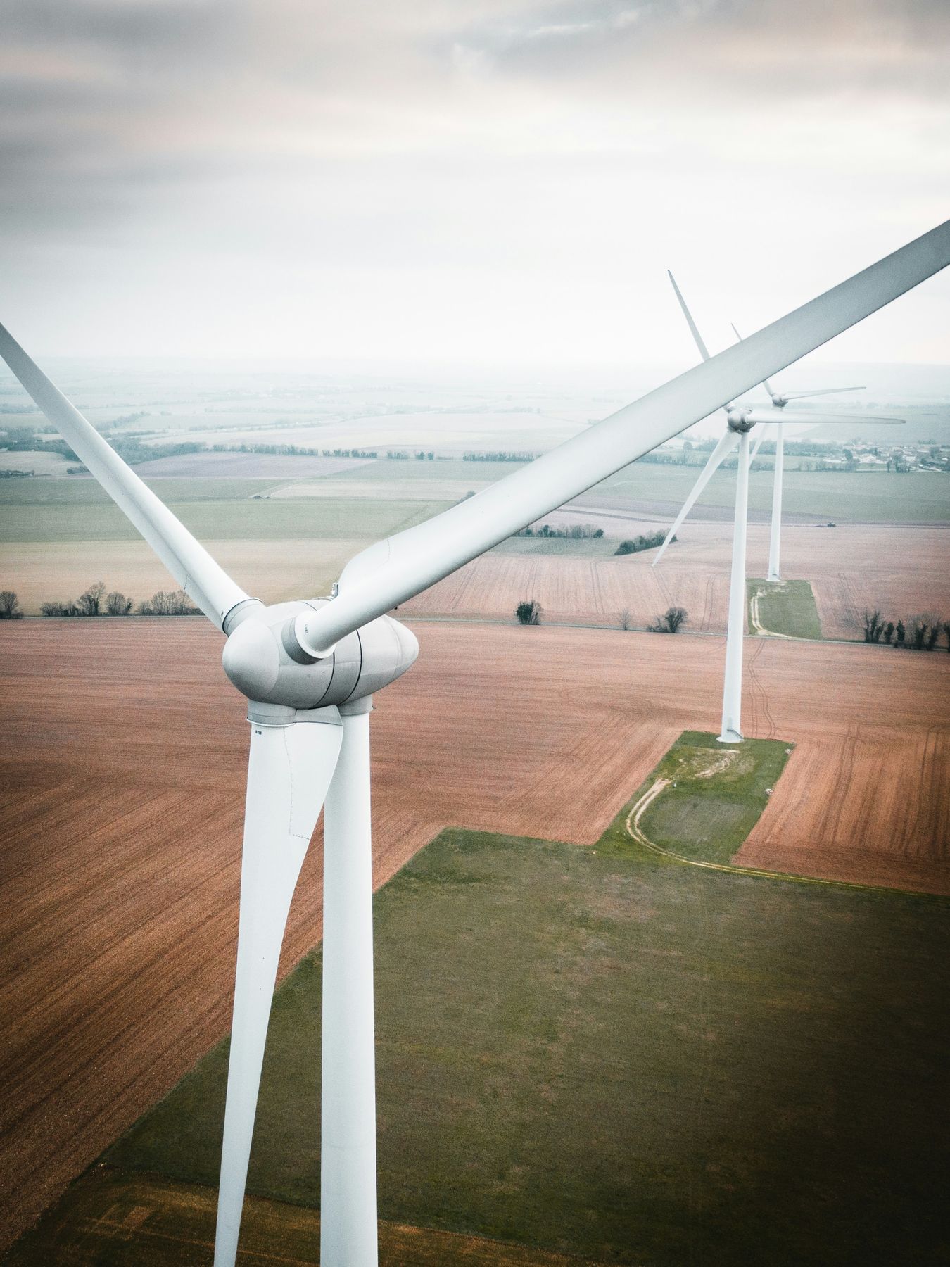 Wind turbines standing over farmland, seen from the air